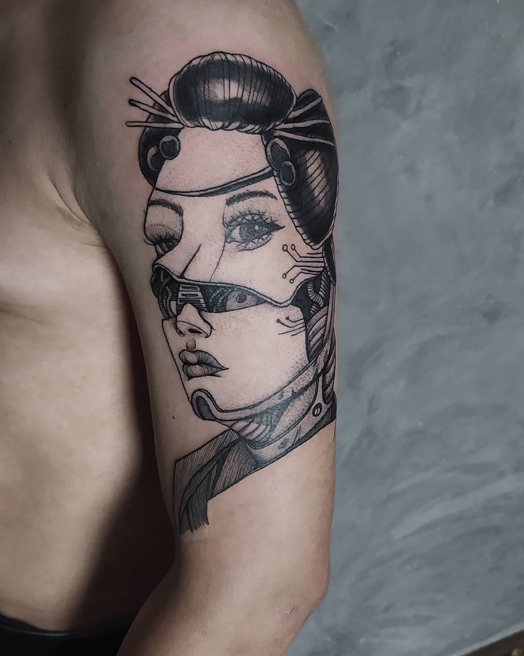 Tattoo of a woman's masked face in a geometric style on an upper arm